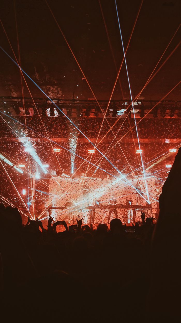 Vibrant concert scene with dynamic light show and audience silhouettes enjoying the night.