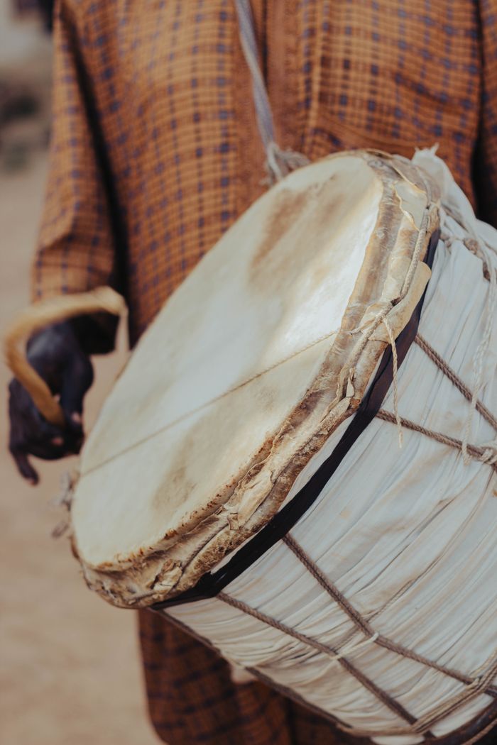 Close-up of a traditional drum being played outdoors, showcasing cultural heritage.