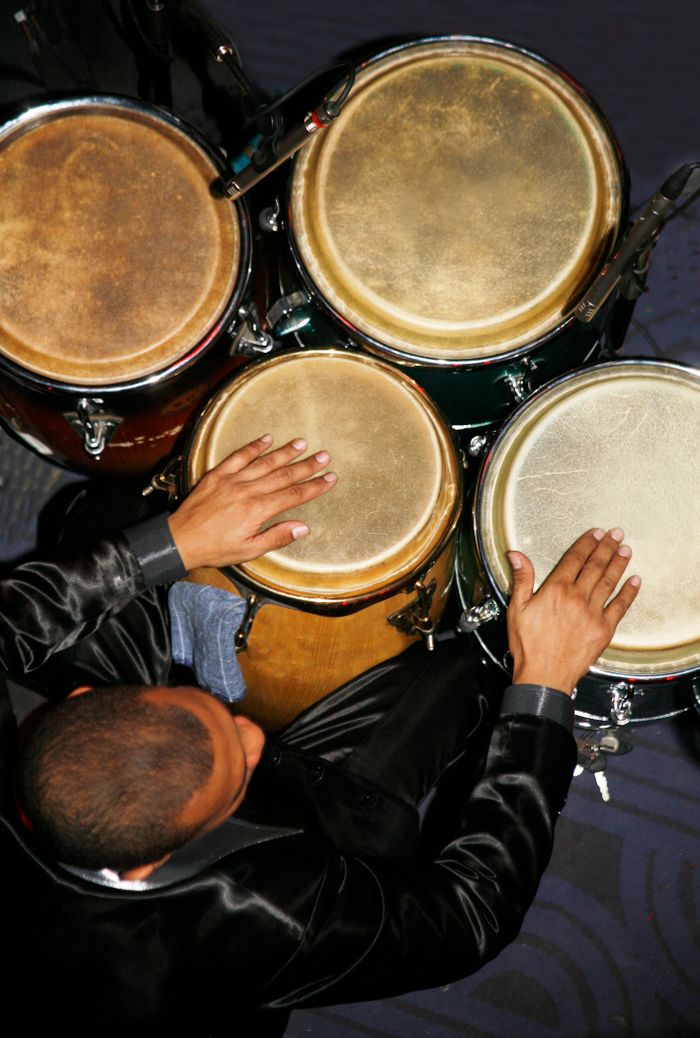 A man skillfully playing congas in an artistic top view, showcasing percussion talent.