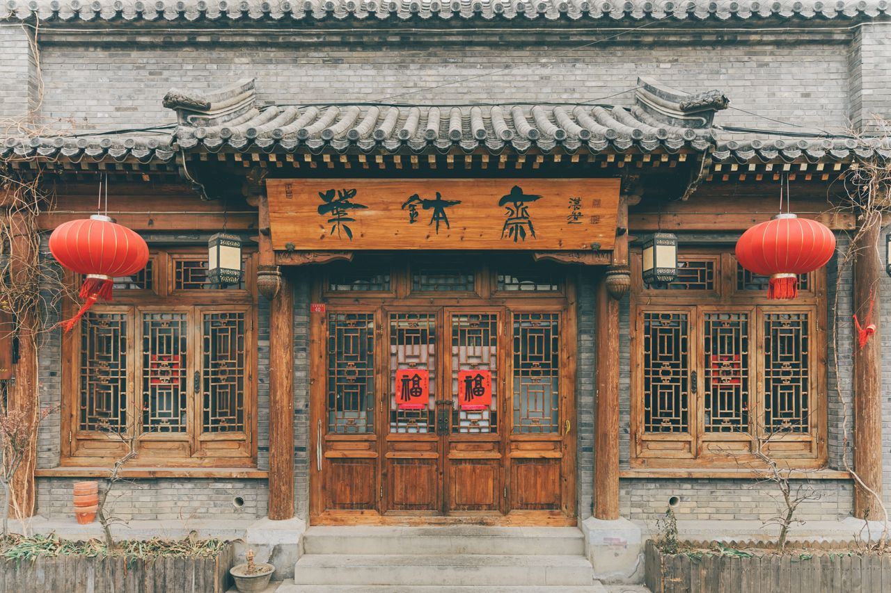 Front view of a traditional Chinese building decorated with red lanterns and wooden doors.